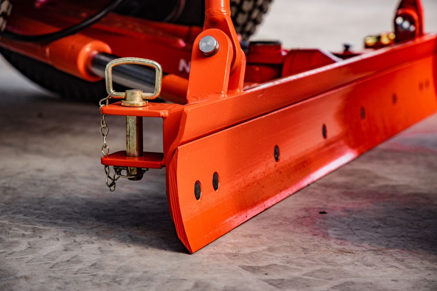 Close up angled view of orange grader blade