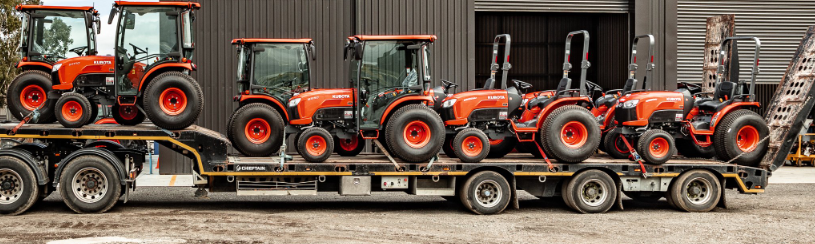 8 Red Kubota Small Tractors on a haulage trailer 